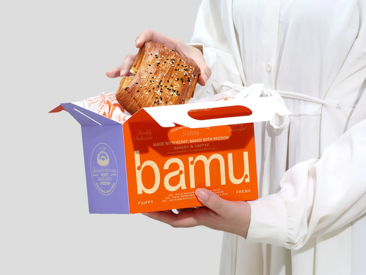 Hands holding Bamu bread and its orange and purple takeaway box