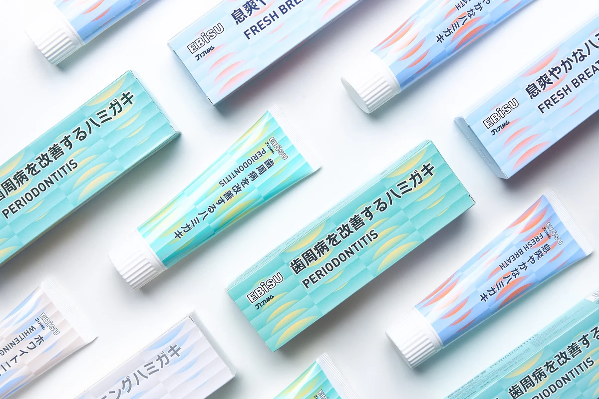 Japanese toothpaste tubes and matching pastel packaging arranged diagonally on white